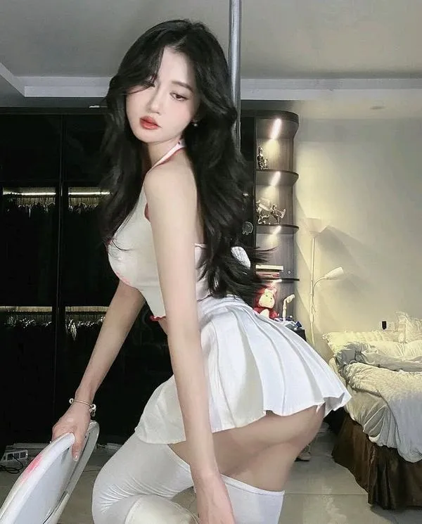 Váy xếp ly, lưng cong nhẹ, tóc dài bồng, gương mặt lạnh, dáng xoay người làm ảnh bật vibe