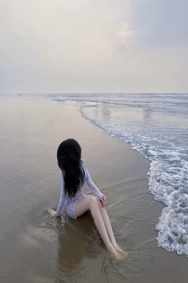Nàng ngồi bên sóng, lưng quay camera, tóc dài rủ, khoảnh khắc lặng và thơ.