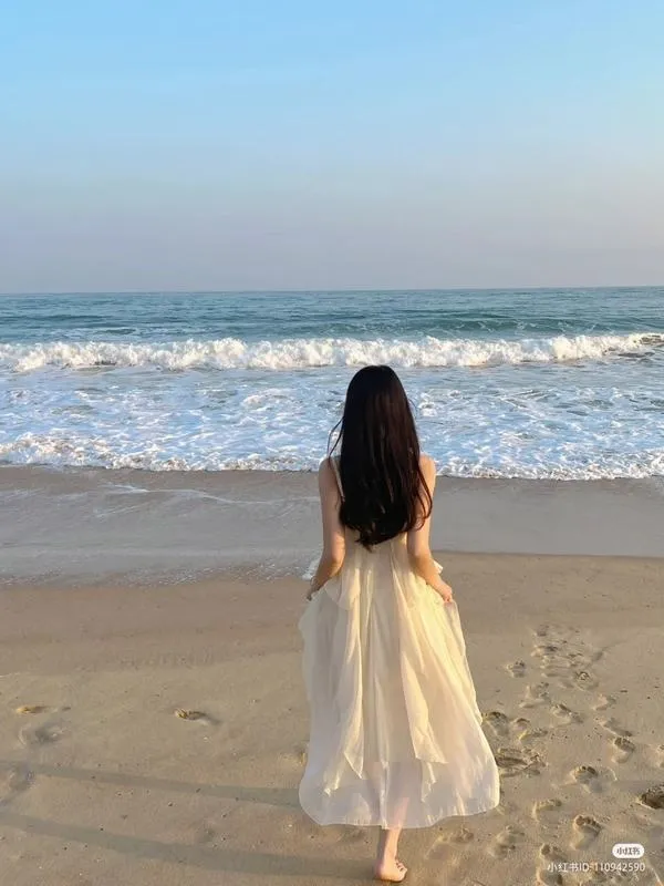 Nàng đứng giữa bãi biển, váy vàng nhạt, tóc thả lưng, bước chậm như đang mơ.