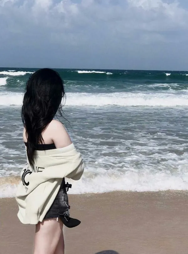 Ánh nắng phản quang trên vai, tóc bay nhẹ, dáng quay lưng tạo cảm giác mơ màng.
