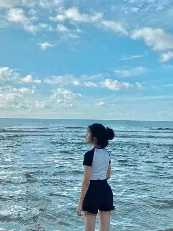 Đường chân trời và mây mỏng làm nền, cô gái quay lưng, tóc dài rủ gọn gàng.
