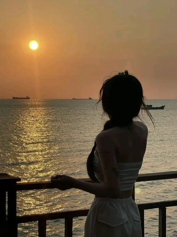 Túi cói cầm hờ bên hông, cô gái quay lưng, tóc dài, vẻ dịu dàng tự nhiên.