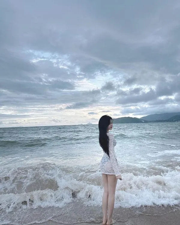 Váy lụa nhẹ chạm gió, cô gái che mặt, bước chậm, dáng mềm và thanh lịch.