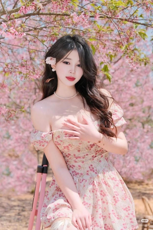 Cô gái xinh mỉm cười bên hoa đào hồng.